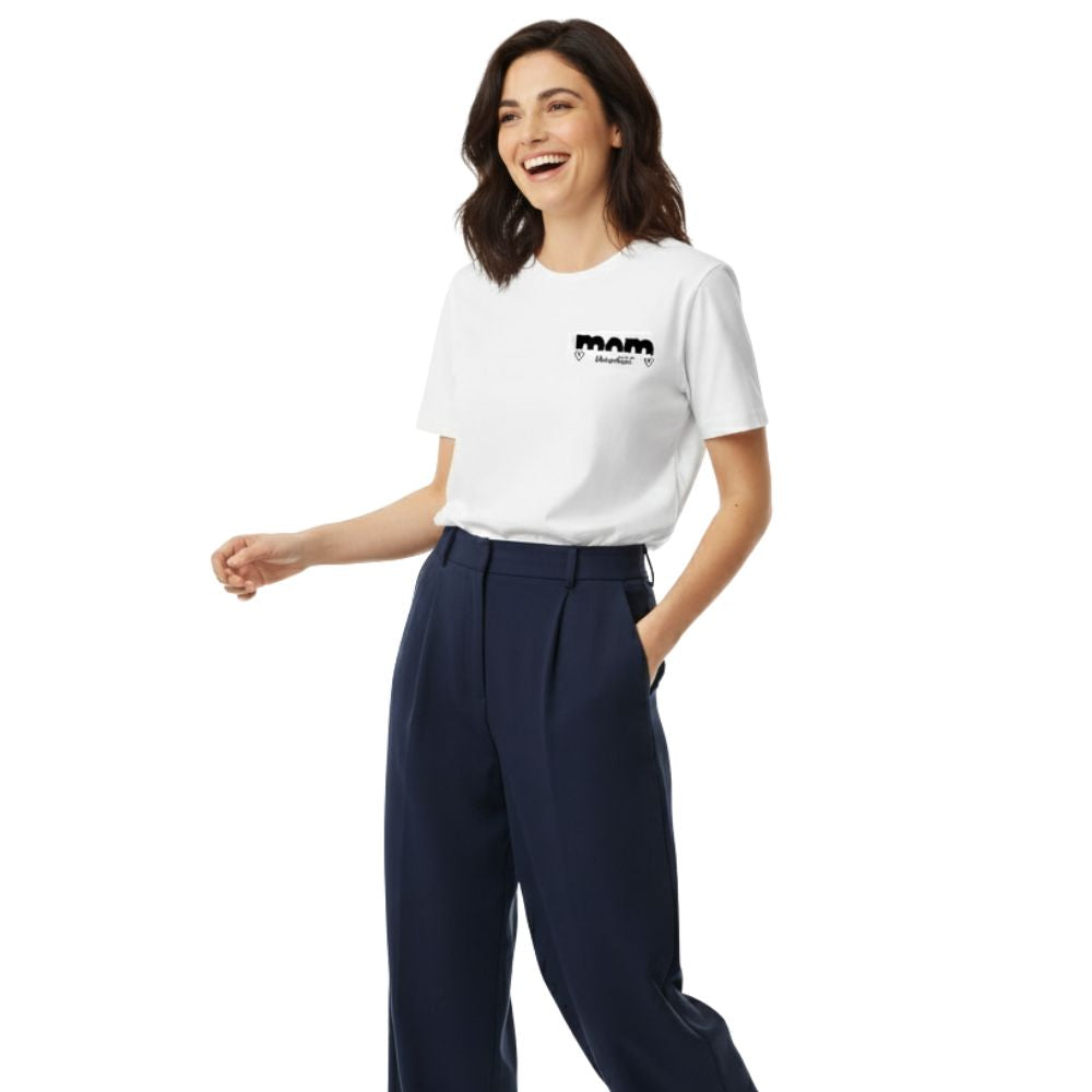 Professionelle Mutter (dunkelhaariges Model) in weißem MOM TRUE T-Shirt und marineblauer Bundfaltenhose, lässig im Gehen.