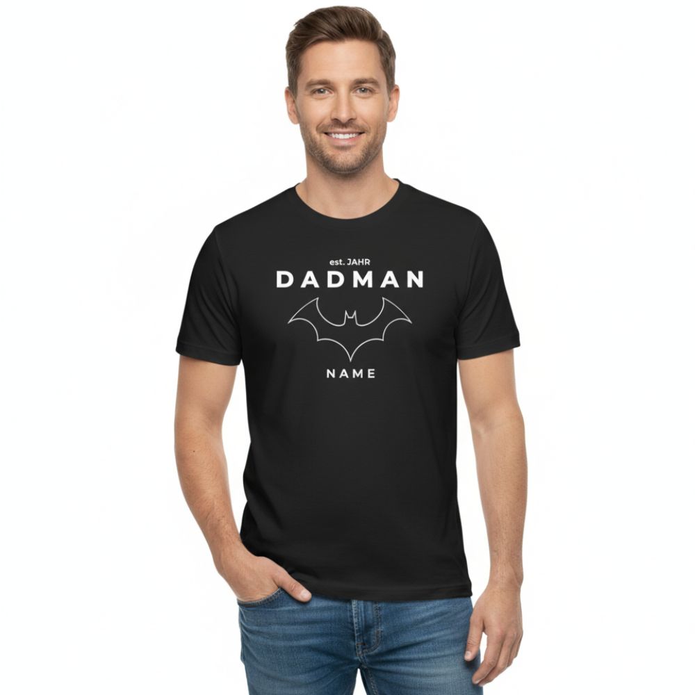 PREMIUM Herren T-Shirt "DADMAN" (180 g/m² Bio-Baumwolle) in Schwarz. Model im modernen Full-Shot, Papa T-Shirt personalisiert mit "est. JAHR" und "NAME". Hochwertiges Vatertagsgeschenk für stilvolle Väter.